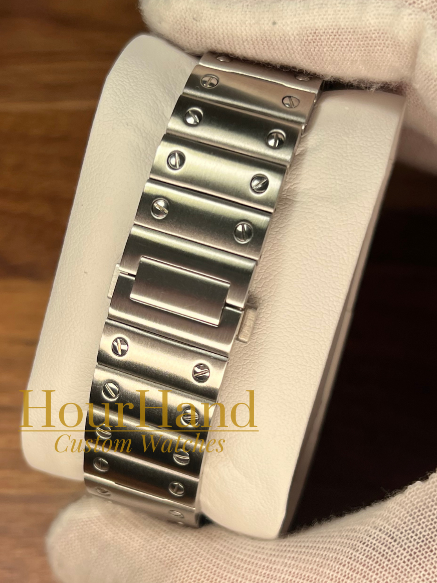 A close-up of a stainless steel watch band mounted on a white display stand, held by a white-gloved hand over a wooden surface. A watermark reading 'HourHand Custom Watches' is visible across the center.
