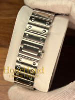 A close-up of a stainless steel watch band mounted on a white display stand, held by a white-gloved hand over a wooden surface. A watermark reading 'HourHand Custom Watches' is visible across the center.